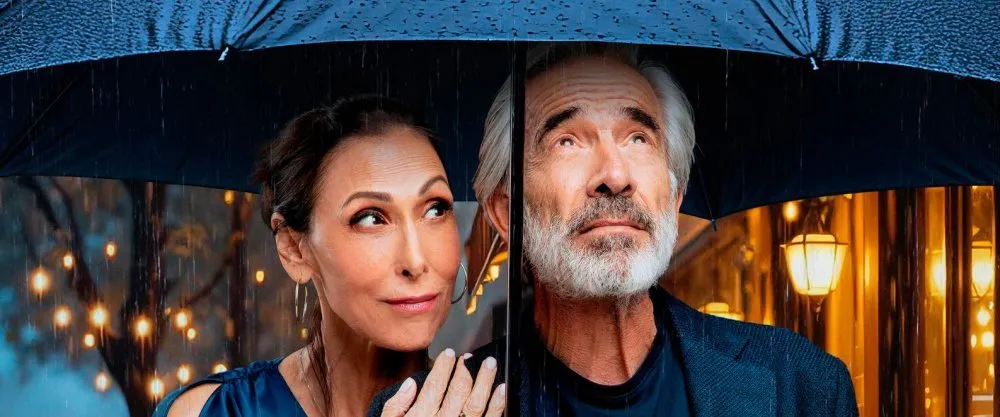 En la imagen se ven a los actores Imanol Arias y Maria Barraco bajo un paragüas
